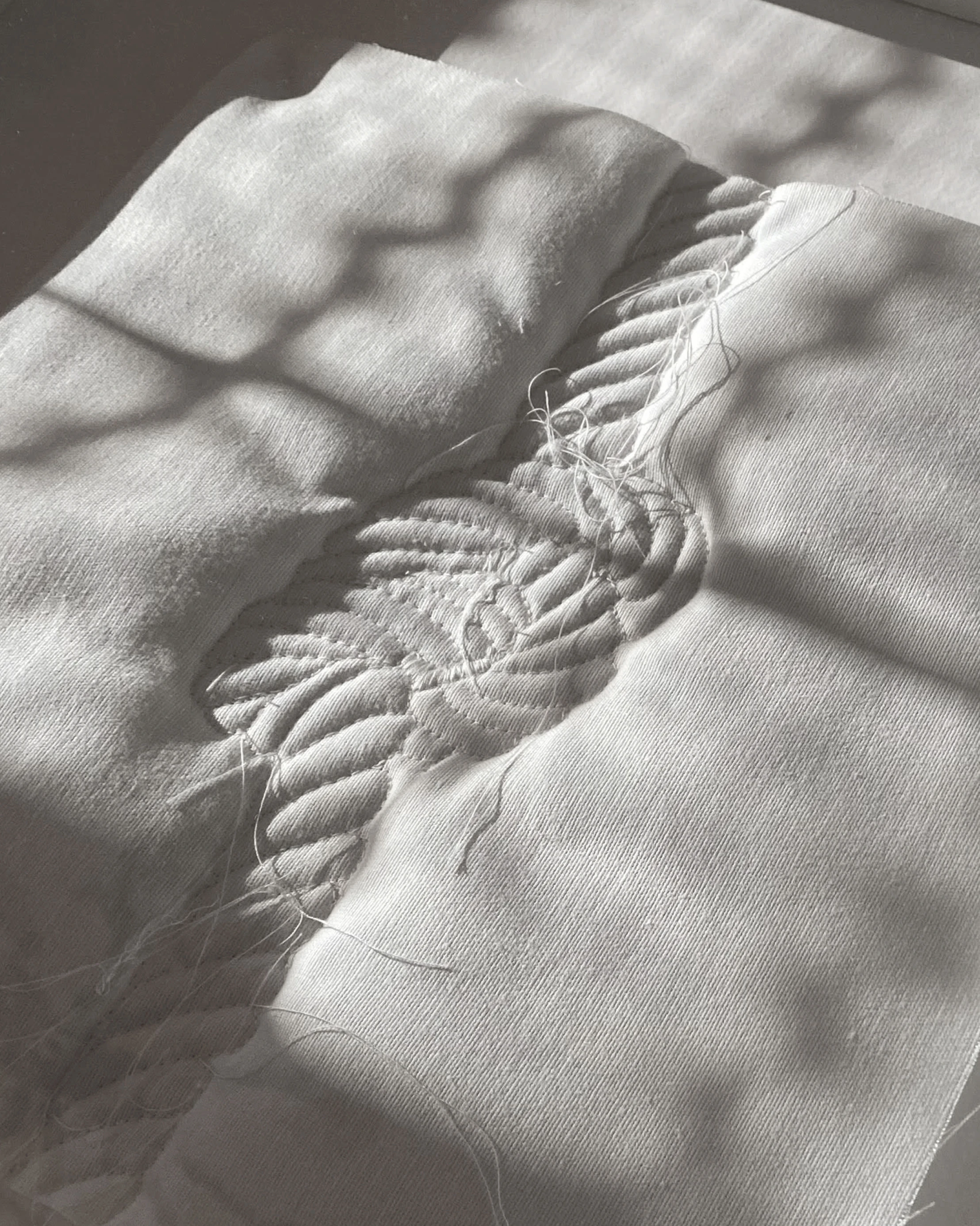 Detail photo of textile artwork made of padding, canvas, and thread. 