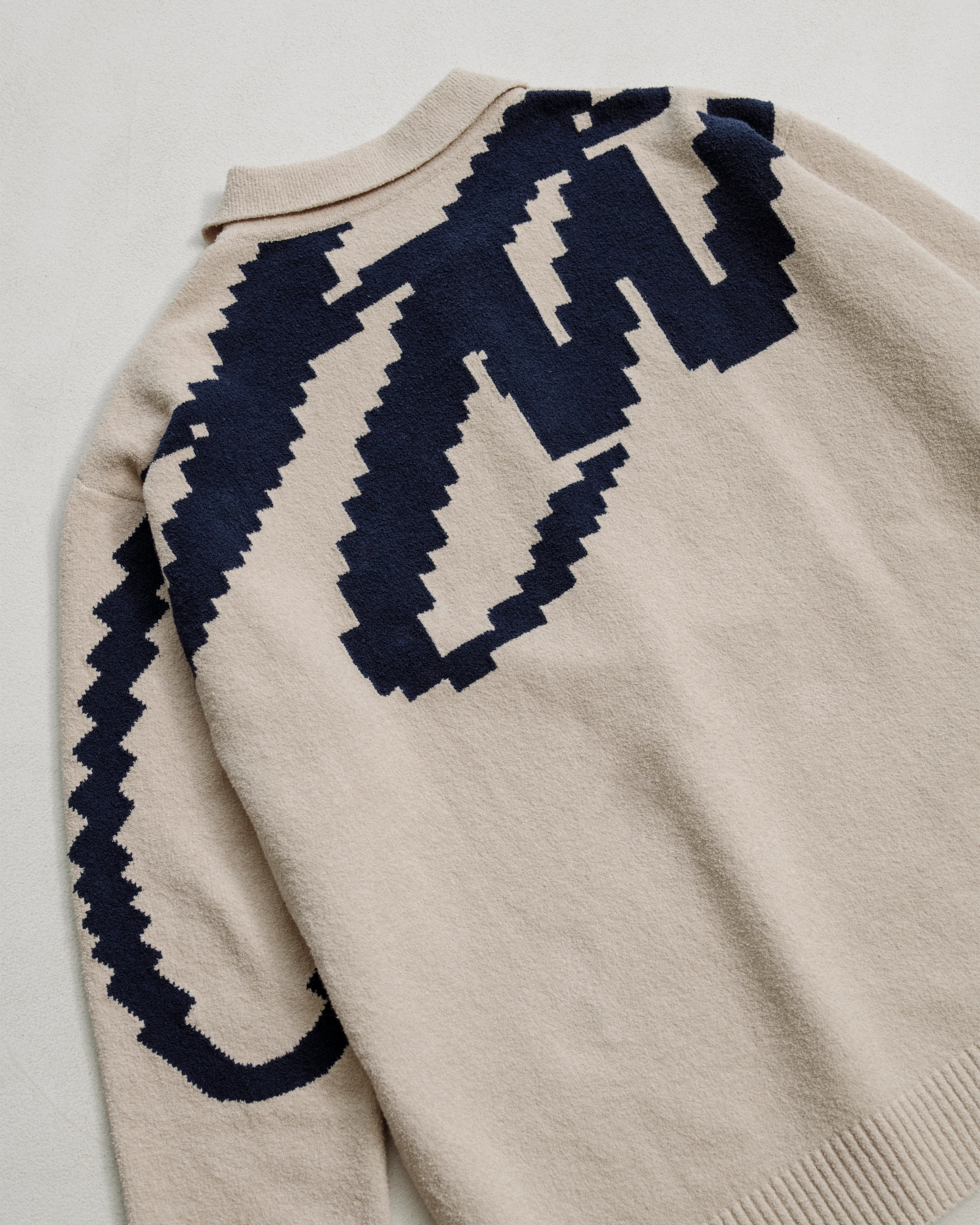 Intarsia knitted polo sweater with contrasting dark blue typography. 