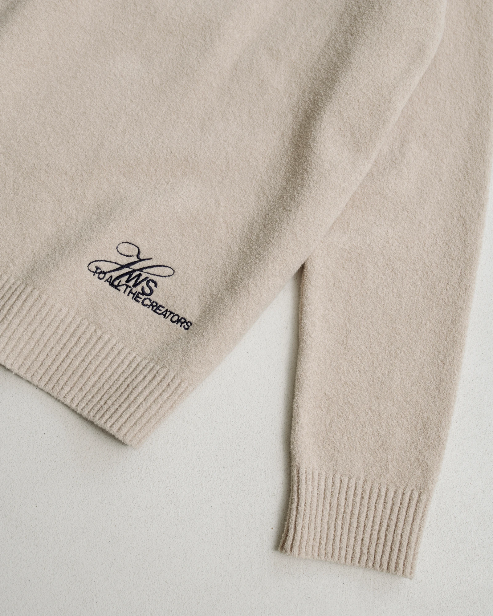 Beige intarsia knitted polo sweater sleeve. 