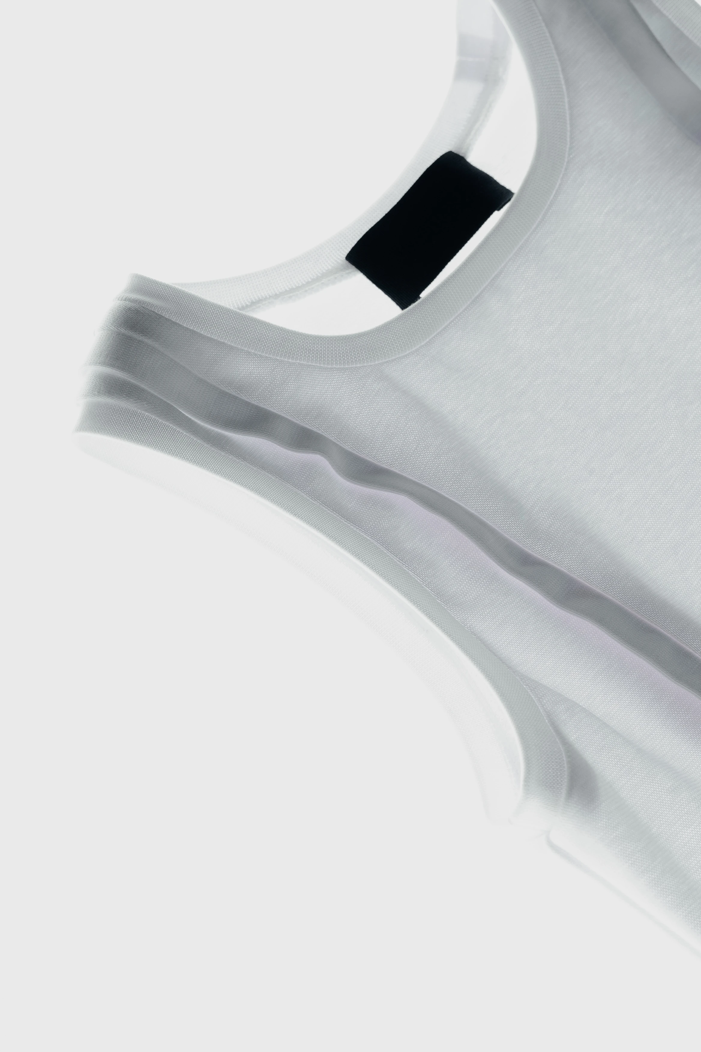 Close-up detail of knitted tank top showing tape finishing along the edges.